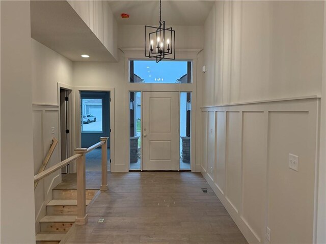 9301 SW Leviathan Ct, Lees Summit, MO 64064 - foyer entrance featuring a decorative wall, a chandelier, wood finished floors, a high ceiling, and a wainscoted wall