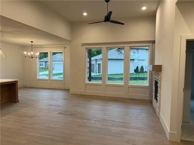 9301 SW Leviathan Ct, Lees Summit, MO 64064 - unfurnished living room with a ceiling fan, a chandelier, light wood-style floors, a stone fireplace, and recessed lighting