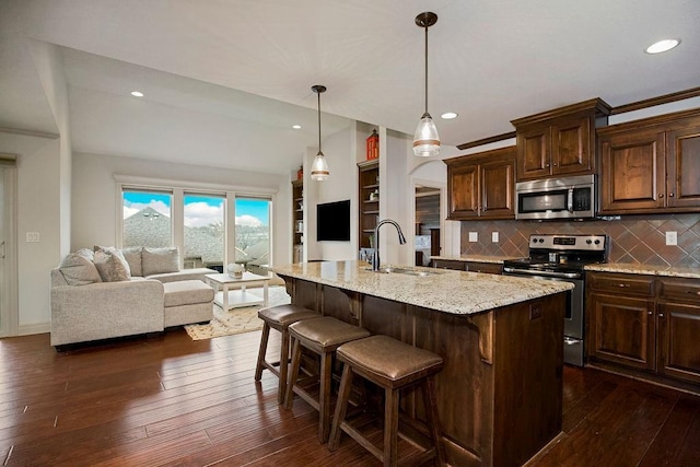 kitchen with sink, tasteful backsplash, a kitchen bar, a kitchen island with sink, and appliances with stainless steel finishes