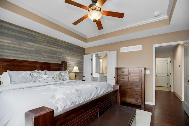 bedroom featuring ceiling fan, dark wood-type flooring, a raised ceiling, wooden walls, and ornamental molding