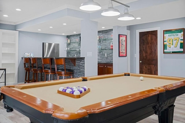 recreation room featuring light wood-type flooring, indoor bar, crown molding, and billiards