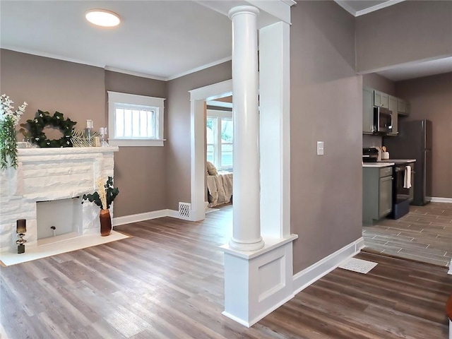 hall featuring decorative columns, dark wood-type flooring, and ornamental molding