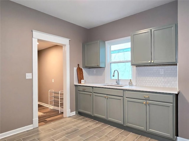 kitchen featuring gray cabinetry, decorative backsplash, sink, and light wood-type flooring