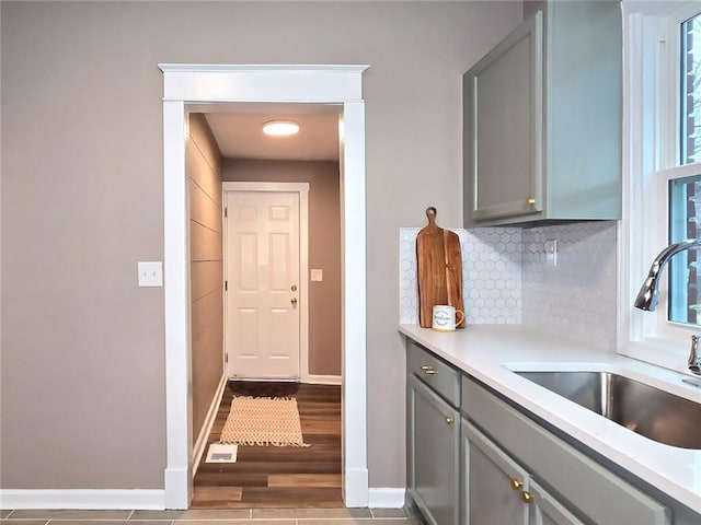 kitchen featuring decorative backsplash, wood-type flooring, gray cabinets, and sink