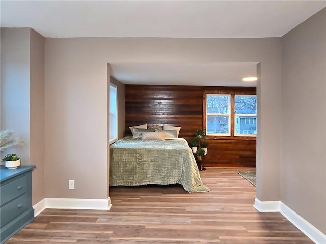 bedroom featuring multiple windows, wood walls, and hardwood / wood-style floors