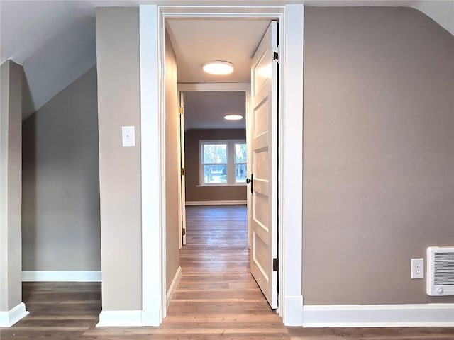 hallway with hardwood / wood-style flooring, heating unit, and lofted ceiling