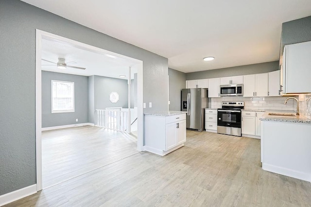 kitchen featuring light stone countertops, decorative backsplash, stainless steel appliances, sink, and white cabinetry