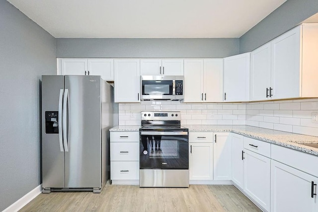 kitchen with white cabinets, light hardwood / wood-style floors, light stone counters, and stainless steel appliances