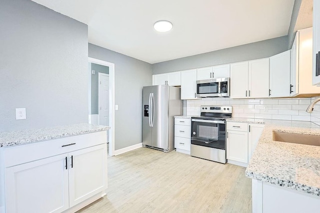 kitchen featuring white cabinetry, sink, light stone countertops, tasteful backsplash, and appliances with stainless steel finishes