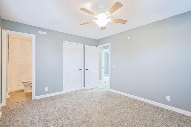 unfurnished bedroom with carpet, a closet, ensuite bathroom, and ceiling fan