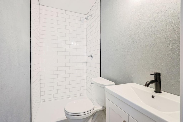 bathroom featuring vanity, toilet, and tiled shower