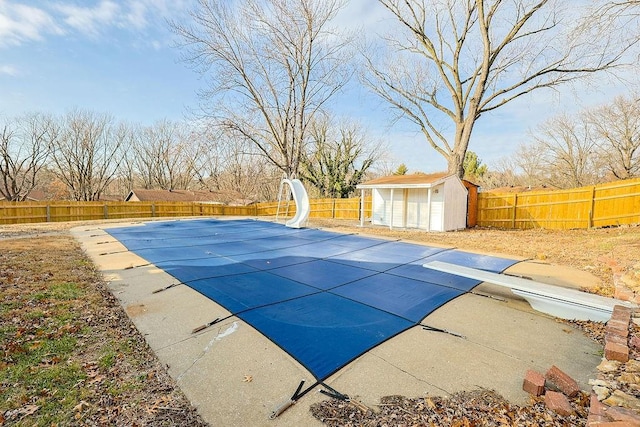 view of pool featuring a diving board, a storage shed, and a water slide