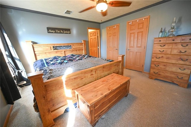 carpeted bedroom featuring two closets, ceiling fan, and ornamental molding