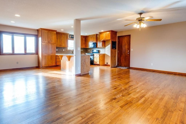 kitchen featuring range with electric cooktop, a center island, ceiling fan, light hardwood / wood-style floors, and a kitchen bar