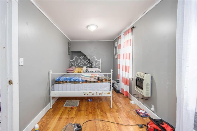 bedroom featuring wood-type flooring, crown molding, and heating unit