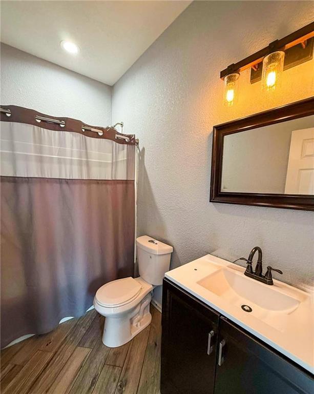 bathroom featuring curtained shower, vanity, wood-type flooring, and toilet