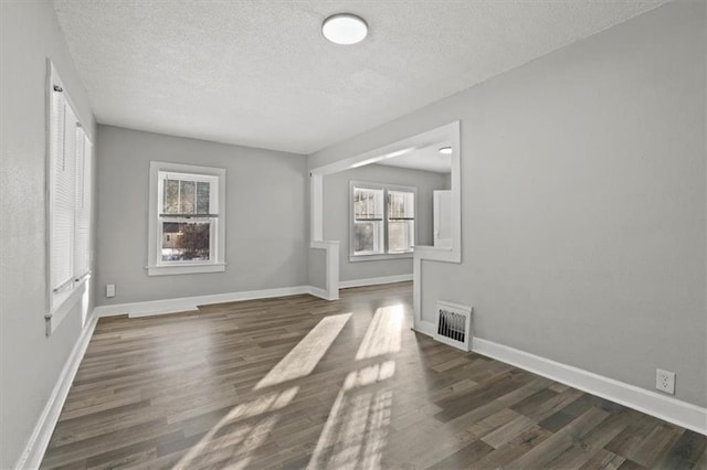 unfurnished room featuring dark wood-type flooring and a wealth of natural light