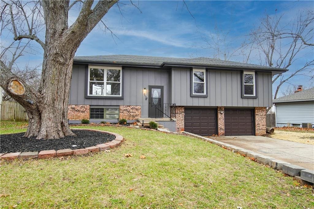 raised ranch with a front lawn and a garage