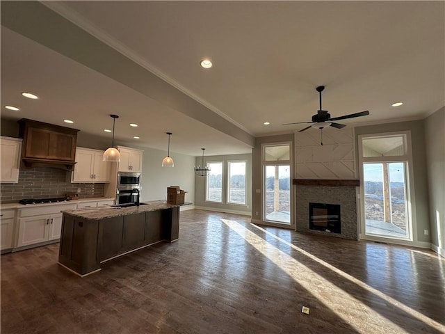 kitchen with gas stovetop, plenty of natural light, a center island with sink, and white cabinets