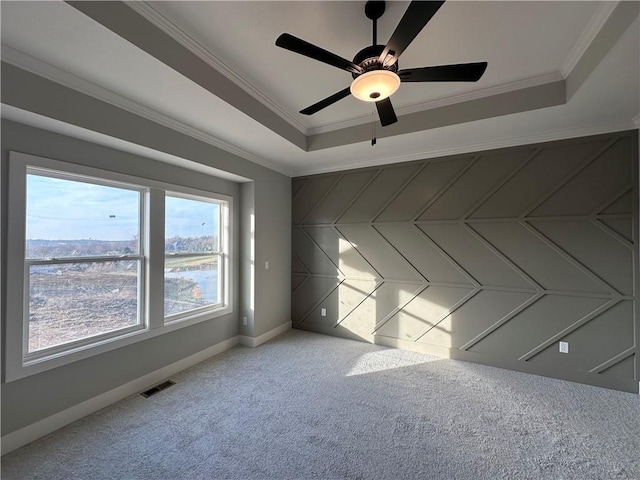 empty room with crown molding, carpet, ceiling fan, and a tray ceiling