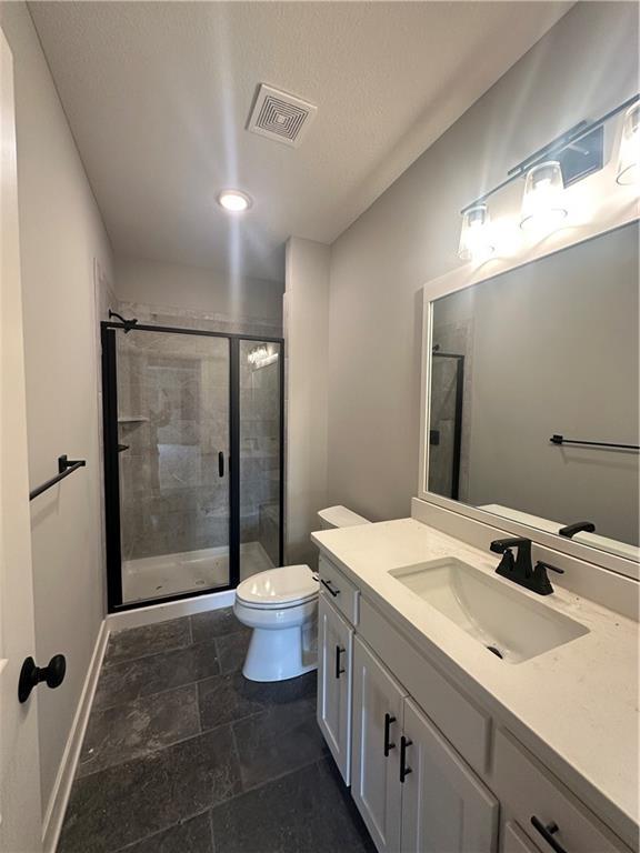 7050 NW Yulich Ct, Parkville, MO 64152 - bathroom with vanity, toilet, baseboards, visible vents, and a stall shower