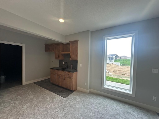 7050 NW Yulich Ct, Parkville, MO 64152 - kitchen featuring dark carpet, baseboards, a wealth of natural light, and dark countertops
