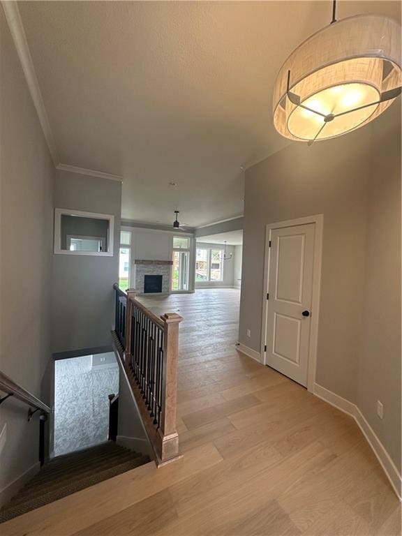 7050 NW Yulich Ct, Parkville, MO 64152 - stairway with crown molding, baseboards, a fireplace, and wood finished floors