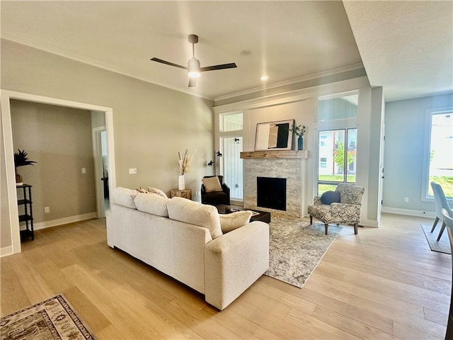 7050 NW Yulich Ct, Parkville, MO 64152 - living room featuring ornamental molding, a stone fireplace, light wood-type flooring, and a ceiling fan