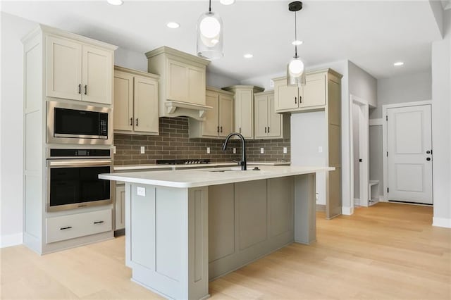 7050 NW Yulich Ct, Parkville, MO 64152 - kitchen with stainless steel appliances, tasteful backsplash, light countertops, an island with sink, and recessed lighting