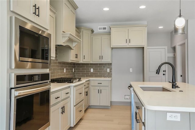 7050 NW Yulich Ct, Parkville, MO 64152 - kitchen with appliances with stainless steel finishes, light wood-type flooring, light countertops, decorative backsplash, and pendant lighting
