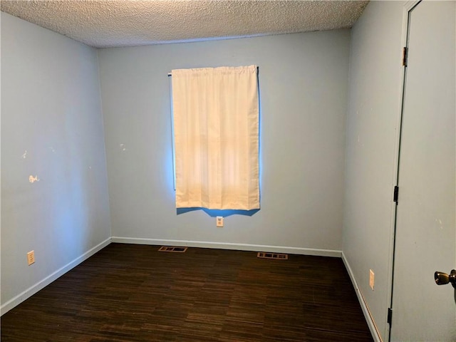 unfurnished room featuring dark hardwood / wood-style flooring and a textured ceiling