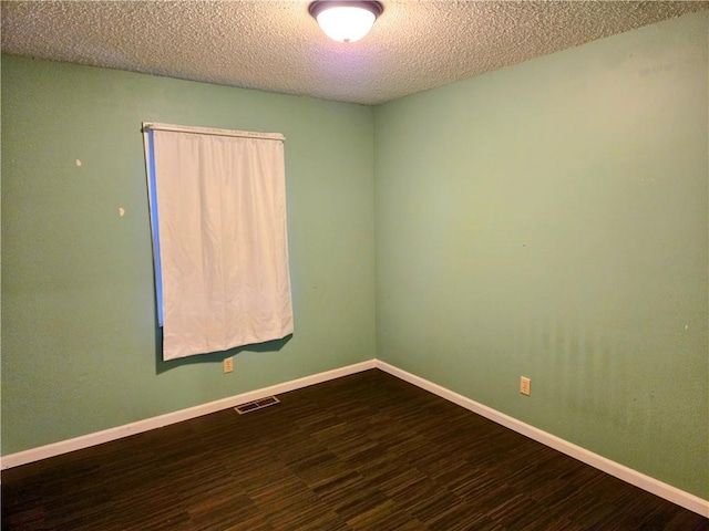 empty room featuring wood-type flooring and a textured ceiling