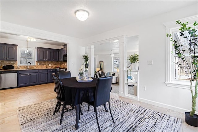 dining area featuring ceiling fan, sink, and decorative columns