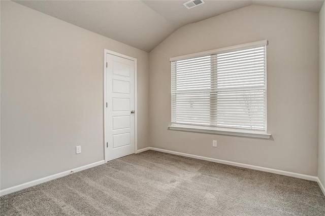 spare room featuring light colored carpet and lofted ceiling