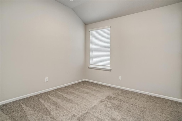 carpeted spare room with vaulted ceiling