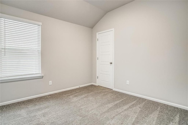 carpeted empty room featuring lofted ceiling