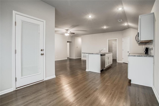 kitchen featuring light stone countertops, appliances with stainless steel finishes, dark hardwood / wood-style flooring, a kitchen island with sink, and ceiling fan