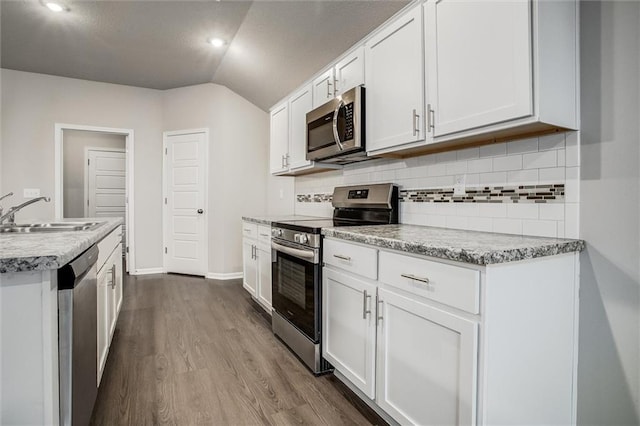 kitchen with appliances with stainless steel finishes, sink, hardwood / wood-style flooring, white cabinets, and lofted ceiling