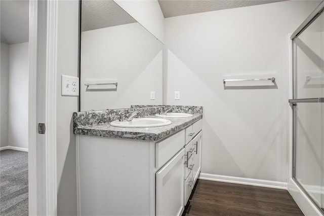 bathroom featuring vanity, an enclosed shower, a textured ceiling, and wood-type flooring