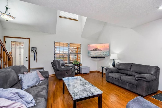 living room featuring wood-type flooring, high vaulted ceiling, and a textured ceiling