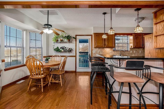 kitchen featuring sink, a kitchen breakfast bar, a wealth of natural light, wood-type flooring, and a textured ceiling