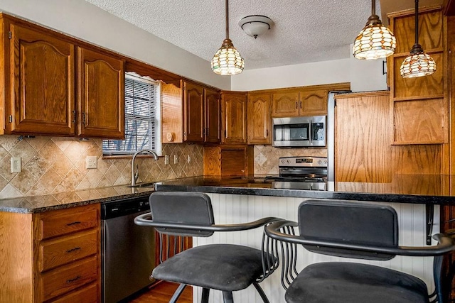 kitchen featuring pendant lighting, sink, a breakfast bar area, appliances with stainless steel finishes, and decorative backsplash