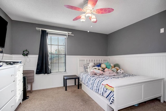 carpeted bedroom featuring ceiling fan and a textured ceiling