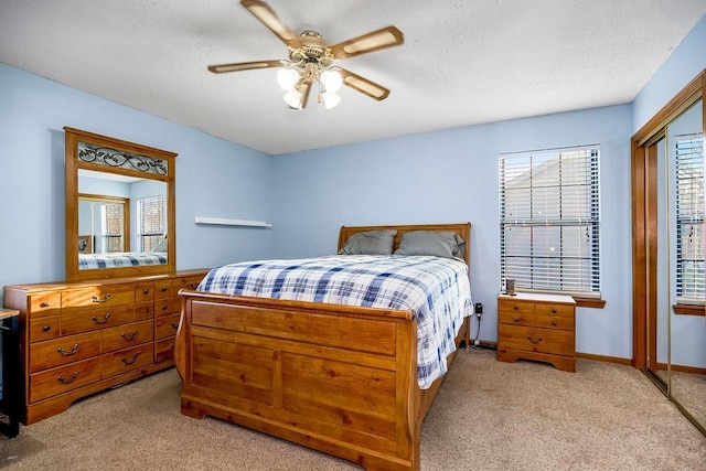 bedroom with ceiling fan, a closet, light carpet, and a textured ceiling