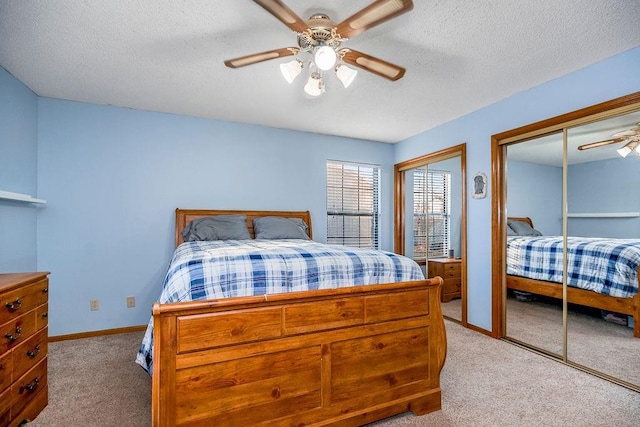 bedroom with light carpet, ceiling fan, two closets, and a textured ceiling