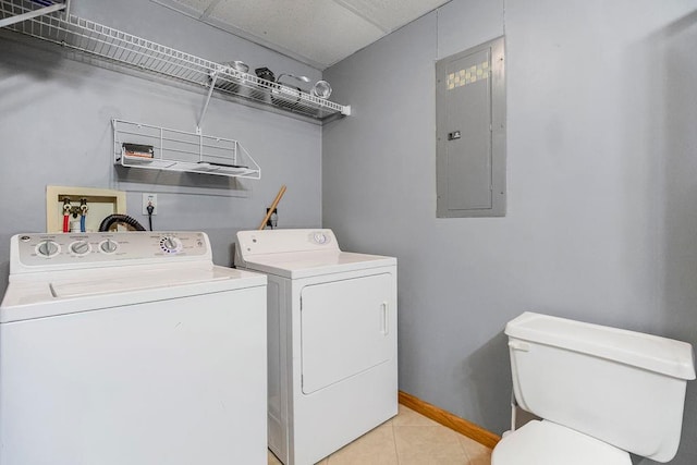 washroom with electric panel, washer and dryer, and light tile patterned floors