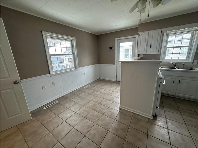 kitchen with ornamental molding, light tile patterned floors, white cabinets, ceiling fan, and sink