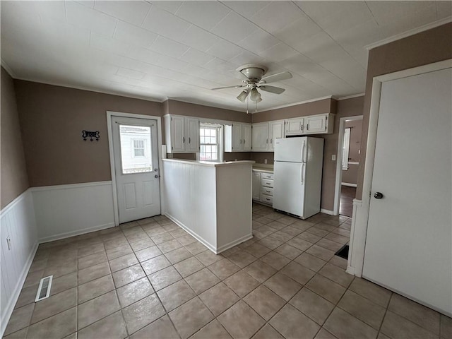 kitchen featuring white cabinetry, white fridge, ceiling fan, light tile patterned floors, and kitchen peninsula