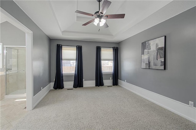 carpeted empty room with ceiling fan and a tray ceiling