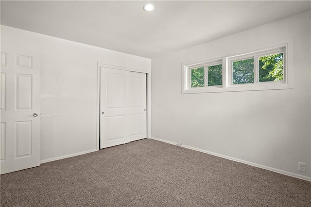 unfurnished bedroom featuring a closet and dark carpet